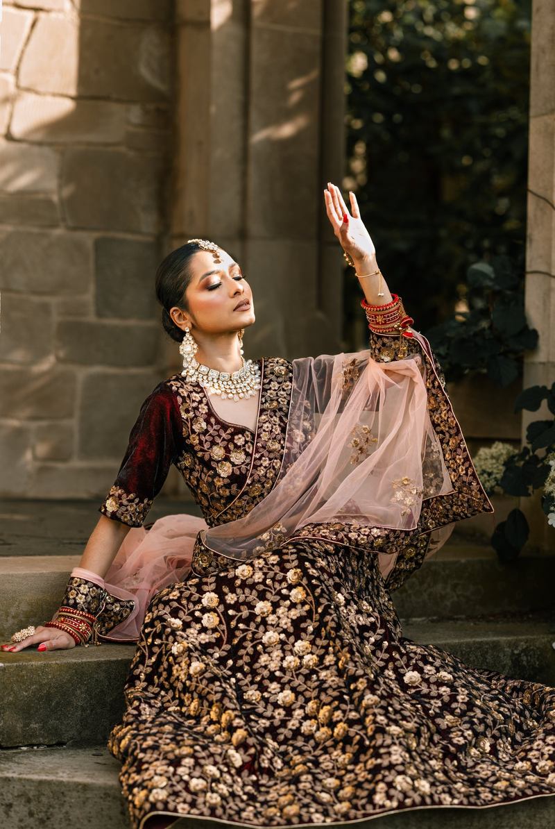 Bride seated on stone steps with one hand raised toward the light