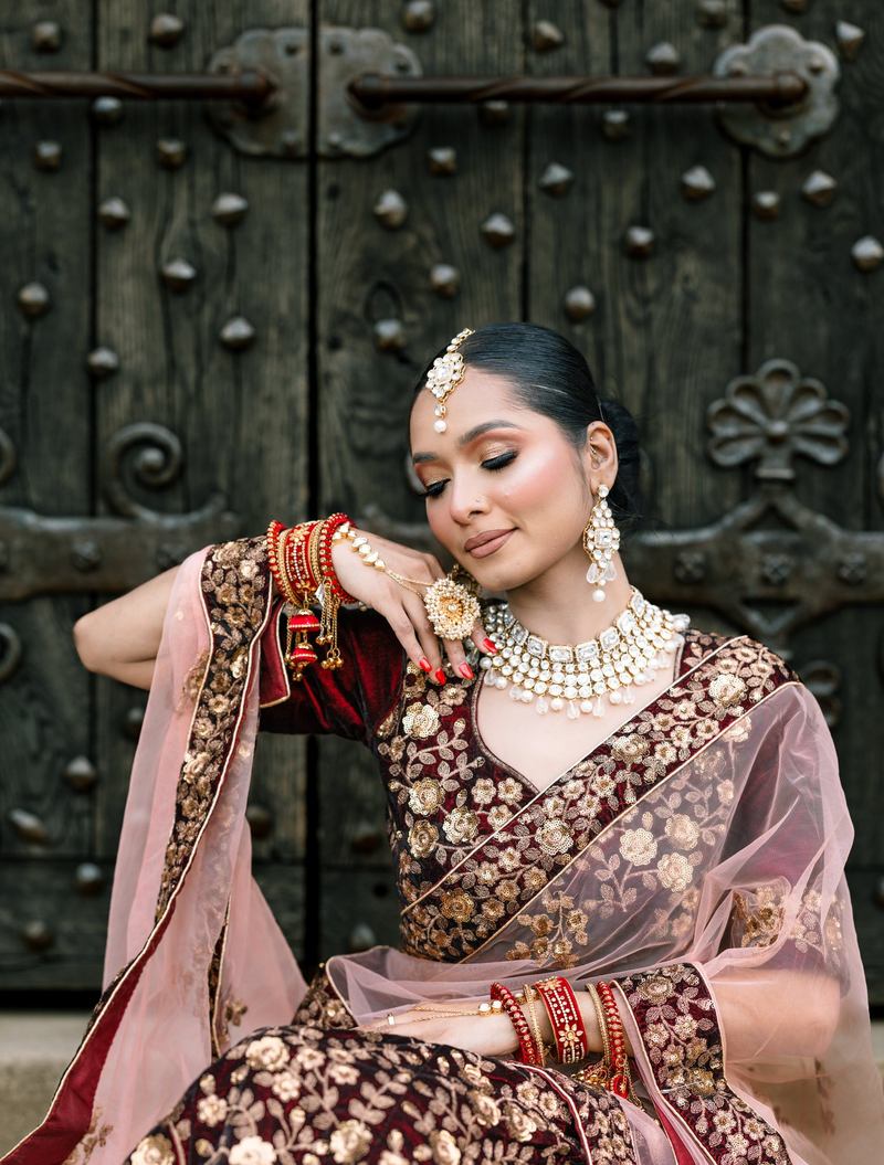 Close portrait of a bride with eyes closed, hand beneath her chin, before an antique studded wooden door